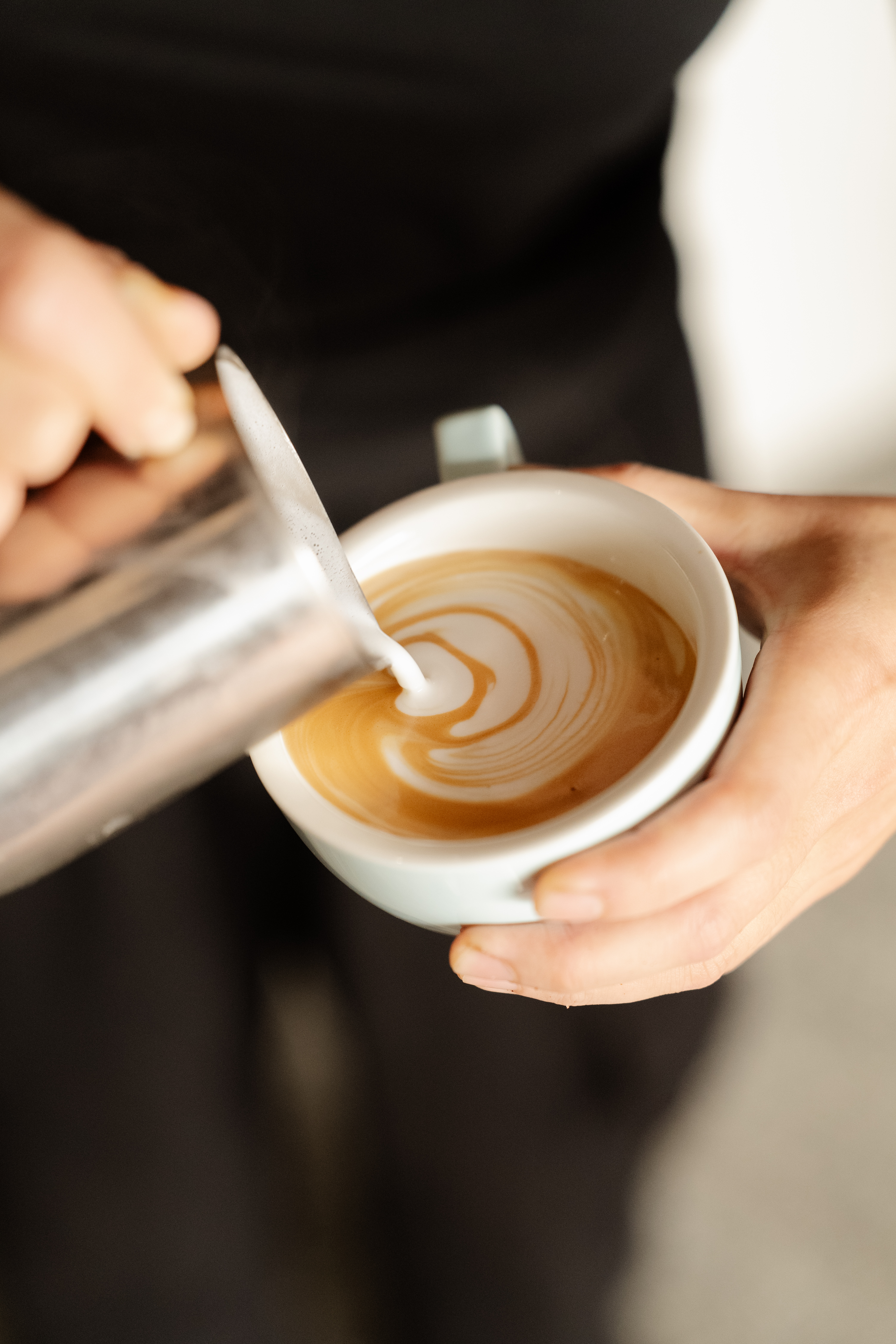 Barista pouring latte art into a freshly brewed coffee at Brass & Bloom